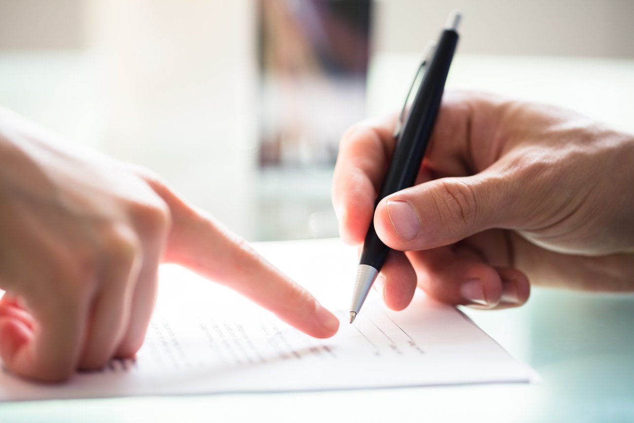 Businessperson Assisting Employee While Signing Document